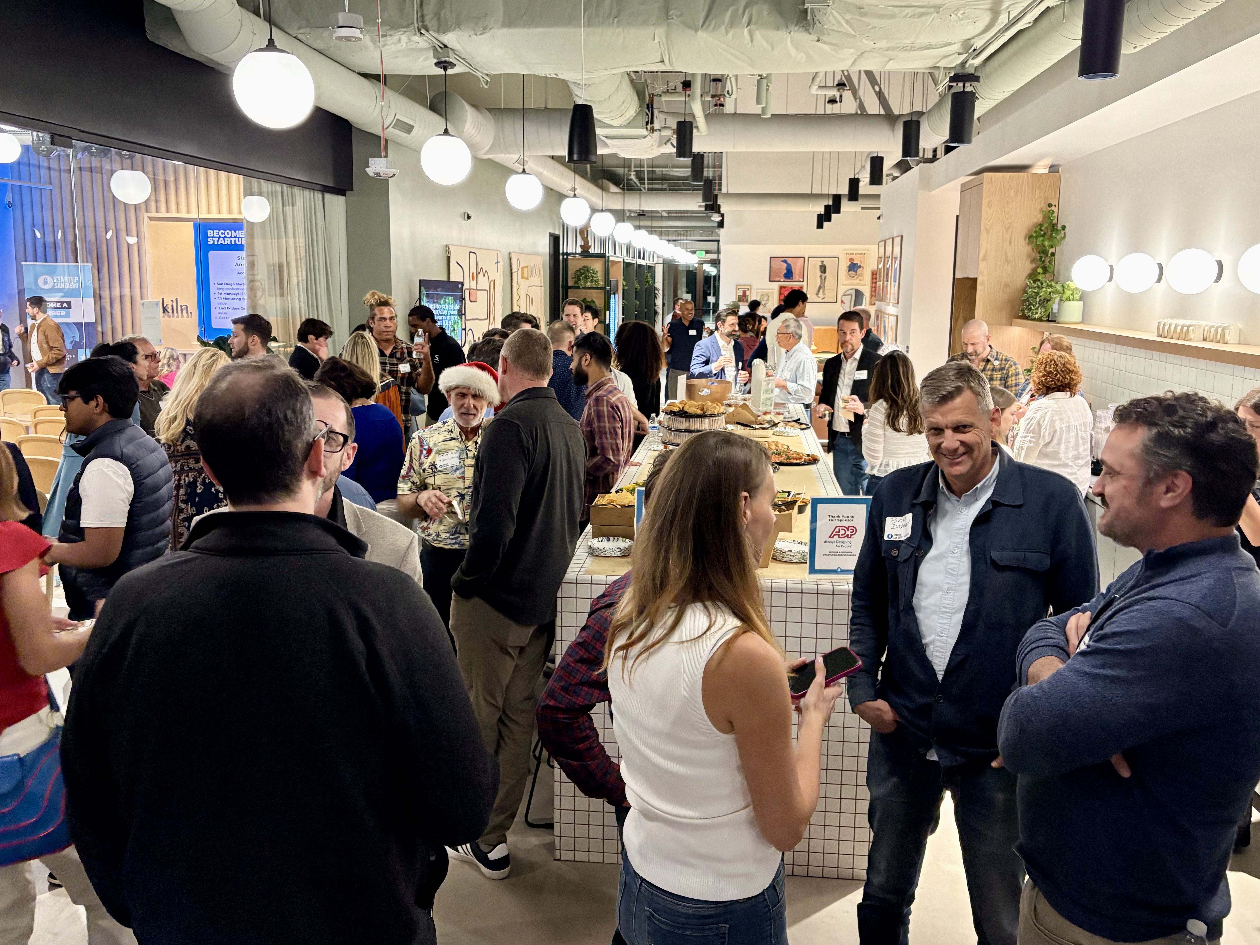 Packed indoor community event with a large diverse crowd at a San Diego tech gathering